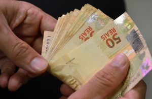 homem segurando notas de 50 reais