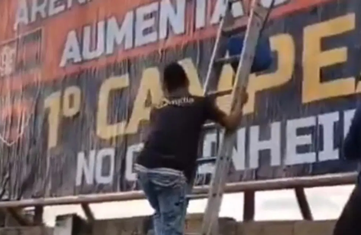 homem colocando outdoor com provocação ao Galo
