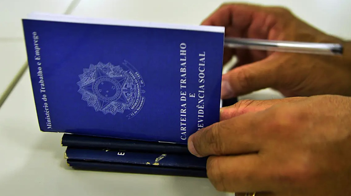 Mão assinando carteira de trabalho