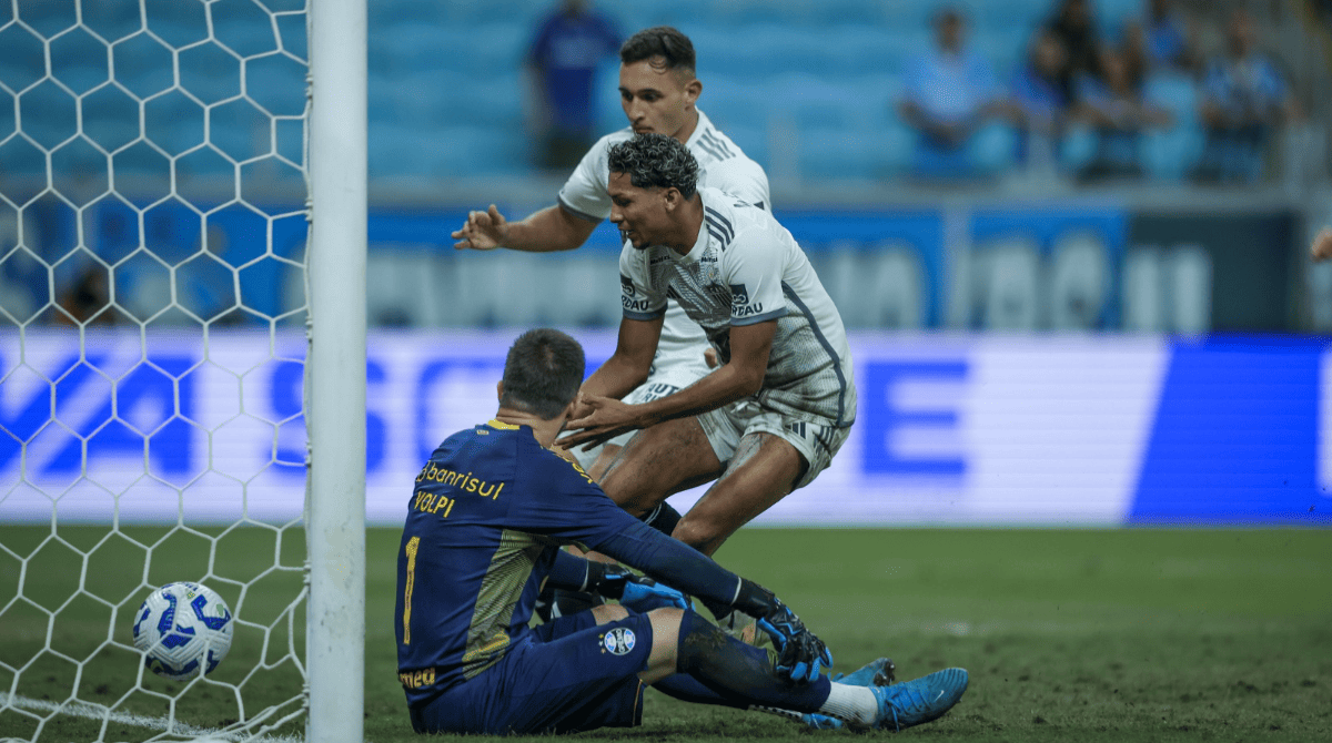 Jogadores do Atlético-MG disputam a bola dentro da pequena área contra o goleiro Tiago Volpi, do Grêmio, que tenta evitar o gol.