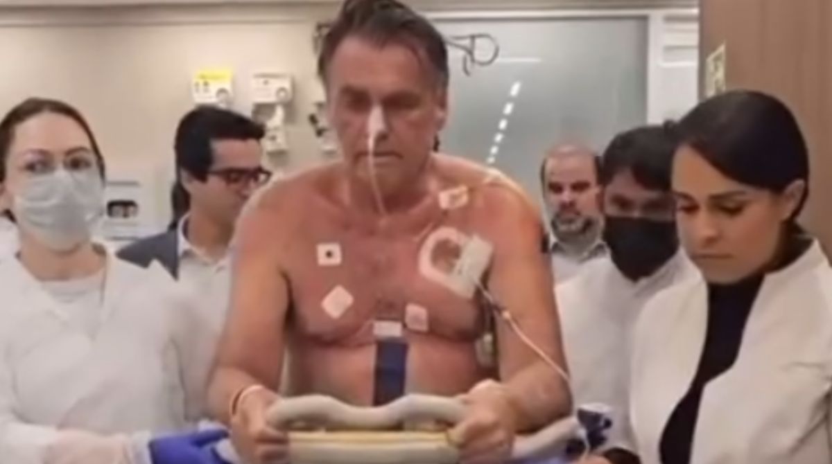 Bolsonaro caminha com auxílio de profissionais da saúde e um andador em hospital de Brasília