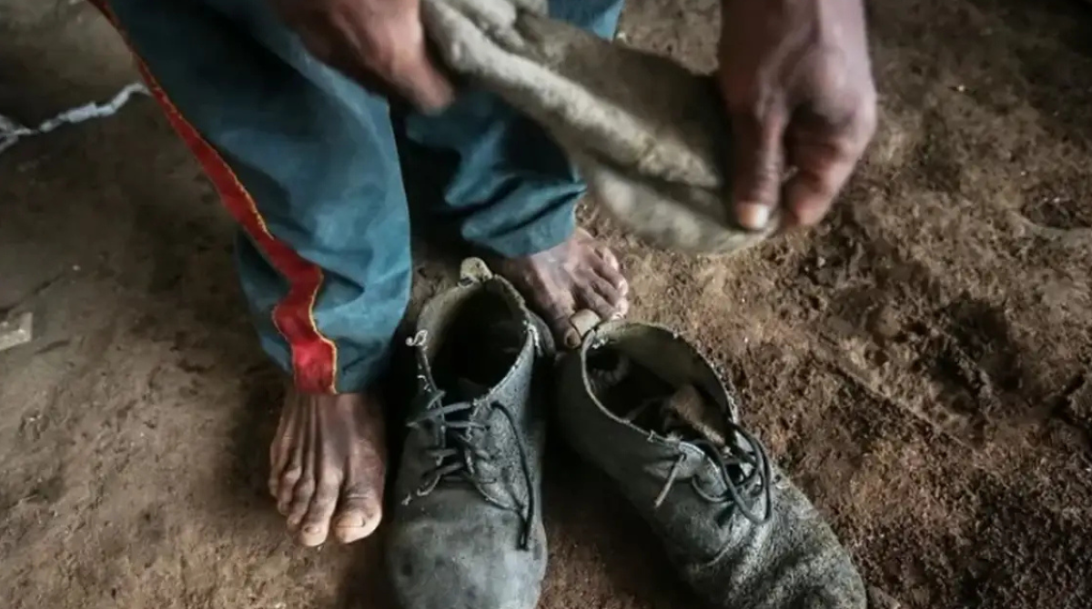 Em primeiro plano, pés descalços de um trabalhador