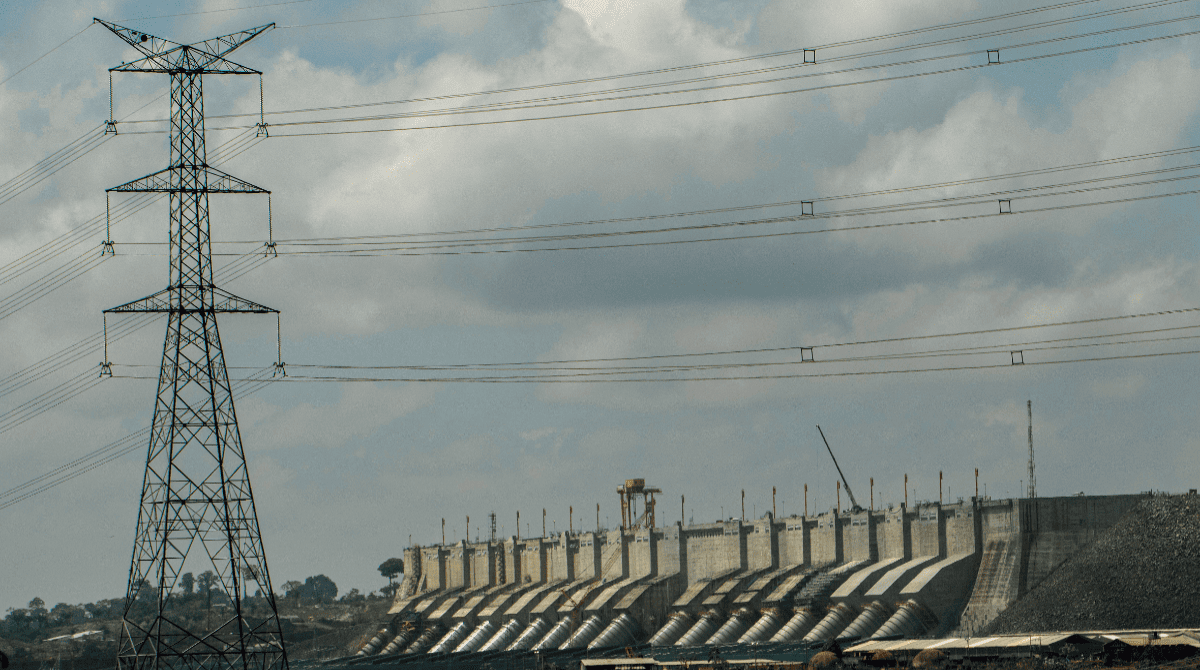 TORRE DE TRANSMISSÃO DE ENERGIA ELÉTRICA COM USINA AO FUNDO