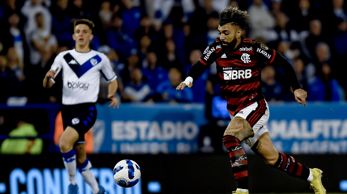 Gabigol em ação pelo Flamengo na Libertadores. Ao fundo, Valentín Gómez cerca a jogada