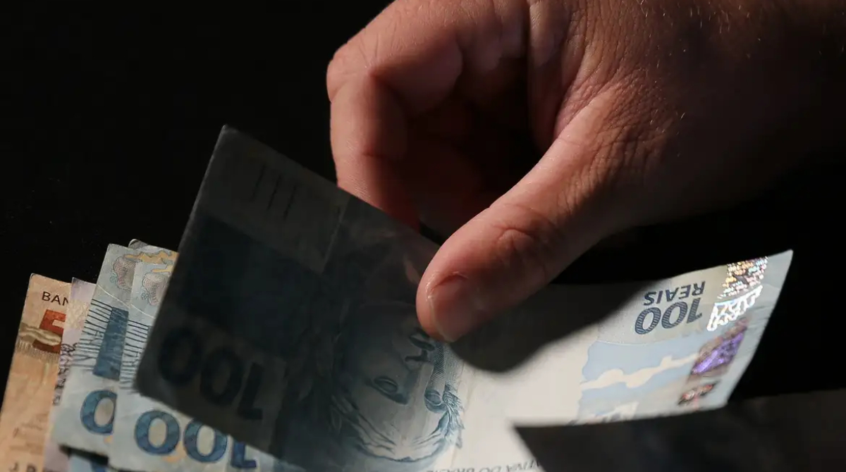 homem passando notas de 100 reais